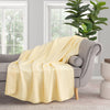 Yellow VelvetLoft Gauze Throw draped neatlyover a grey sofa in a staged room.