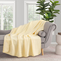 Yellow VelvetLoft Gauze Throw draped neatlyover a grey sofa in a staged room.