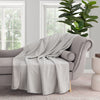 Grey VelvetLoft Gauze Throw draped neatly over a grey chair in a staged room.