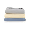 Grey, yellow, and blue VelvetLoft Gauze Throws stacked neatly on a white surface.