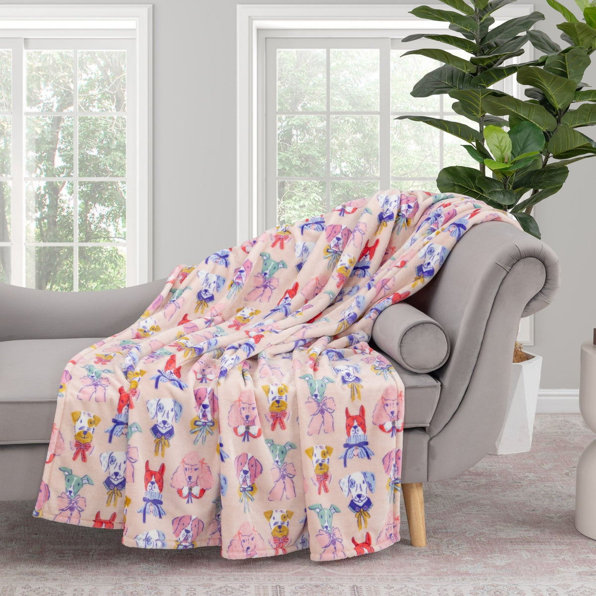 Krissy Mast Artist Series printed dog print throw draped neatly over a grey sofa in a staged room.