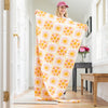 A woman holding up a sun printed throw in a bright room.