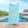 Blue peanuts beach towel held up by a person standing by a pool.