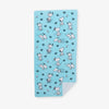 Blue Peanuts beach towel laid flat on a white surface.