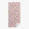 A pink Peanuts beach towel laid flat on a white surface.