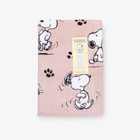 A pink Peanuts beach towel folded neatly on a white surface.