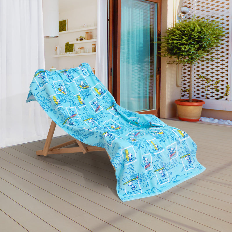 A blue peanuts beach towel draped over a wooden chair on a patio.