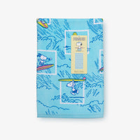 A blue peanuts beach towel folded neatly on a white surface.