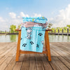 Peanuts beach towels stacked neatly on a wooden chair by a pond.