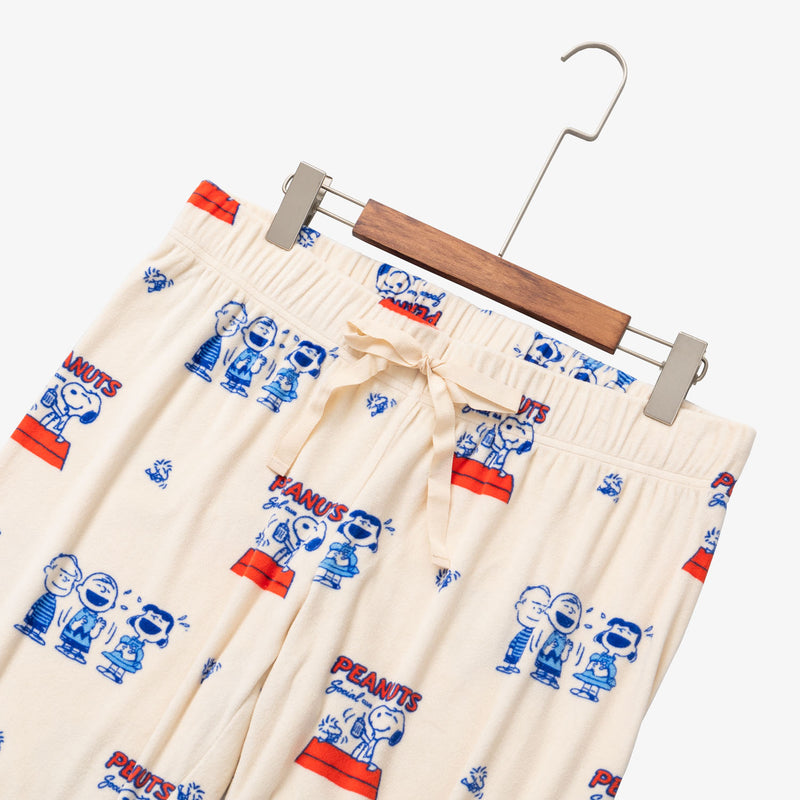 Peanuts 75th Anniversary printed lounge pants laid flat on a white surface with a hanger.
