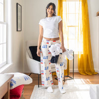A woman standing in a  living room holding a snoopy plush smiling.