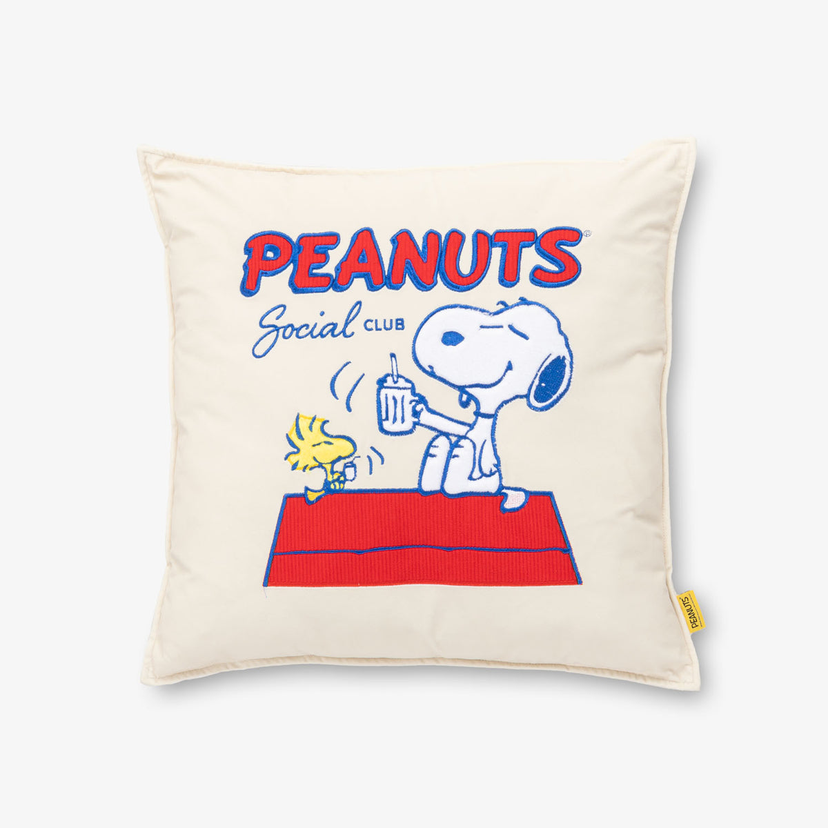 Peanuts Social Club Pillow sitting on a white surface.