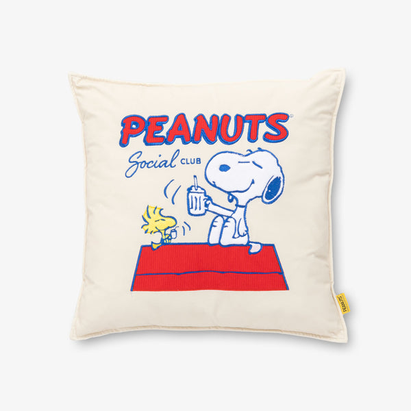 Peanuts Social Club Pillow sitting on a white surface.