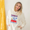 A woman wearing a cream Peanuts lounge hoodie.