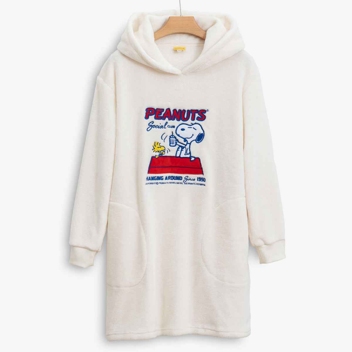 Peanuts social club embroidered lounge hoodie hung on a hanger on a white surface.