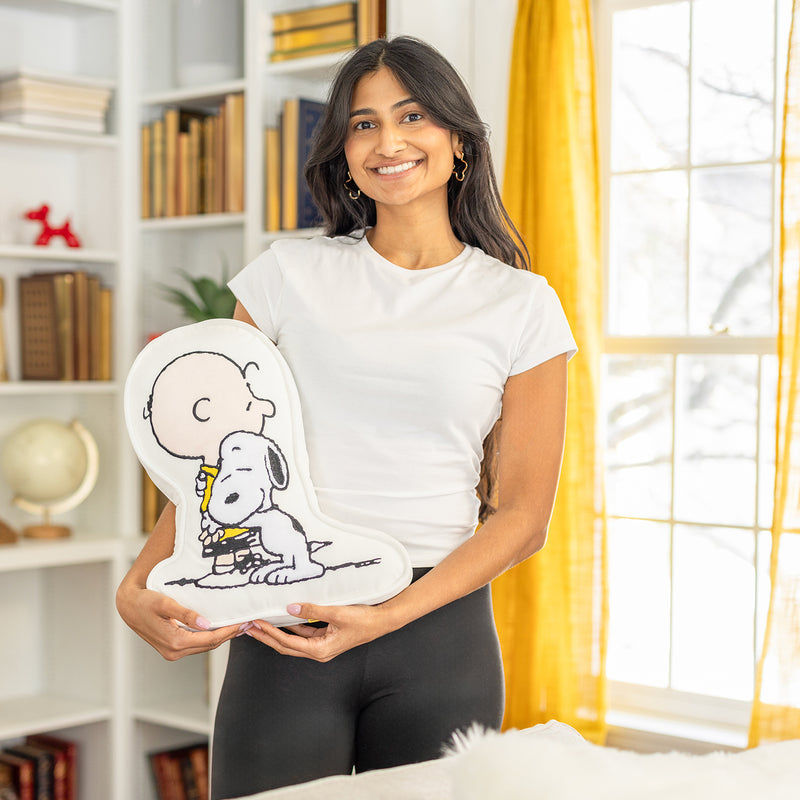 A woman holding a Charlie Brown & Snoopy embroidered pillow.