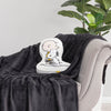 Charlie Brown & Snoopy embroidered pillow sitting on a black throw on a grey chair.