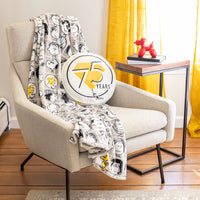 Peanuts 75th Anniversary Throw and Pillow on a beige chair.