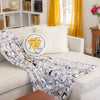 Peanuts 75th Anniversary Throw and Pillow on a beige sofa.
