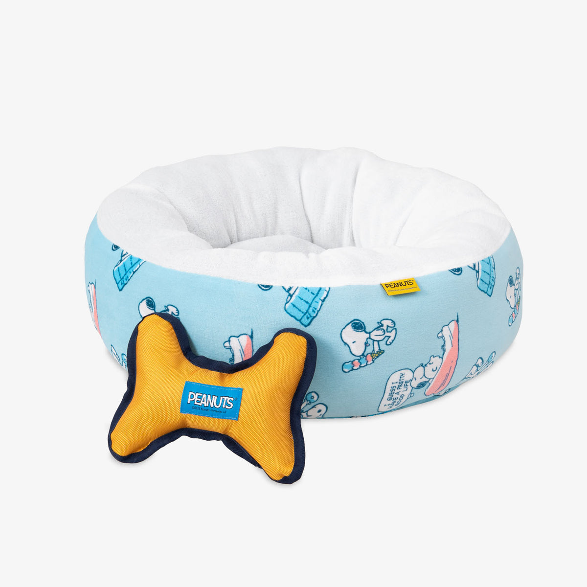 Peanuts pet bed and dog toy set siting on a white surface.