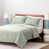 Bed with green bedding and white pillows in a bedroom setting.