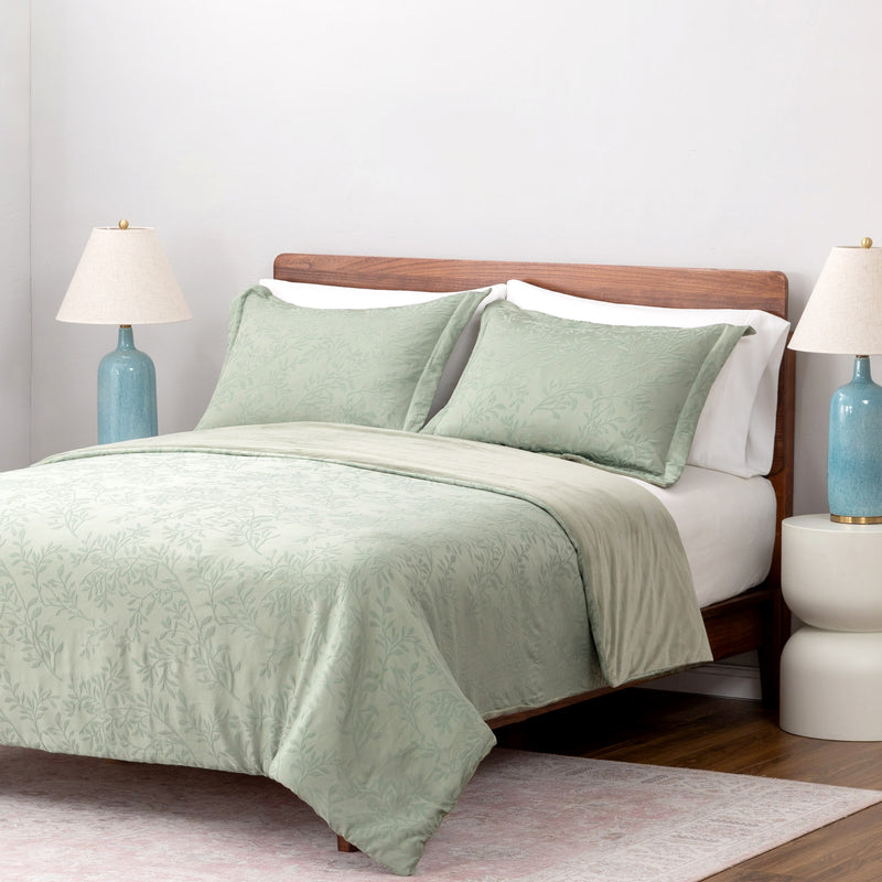 Bed with green bedding and white pillows in a bedroom setting.