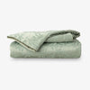 Folded green duvet with leaf pattern on a white background