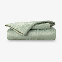 Folded green duvet with leaf pattern on a white background