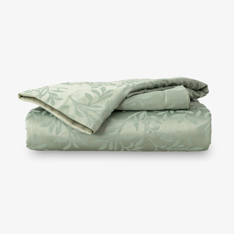 Folded green duvet with leaf pattern on a white background