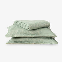 Set of green floral-patterned bedding on a white background