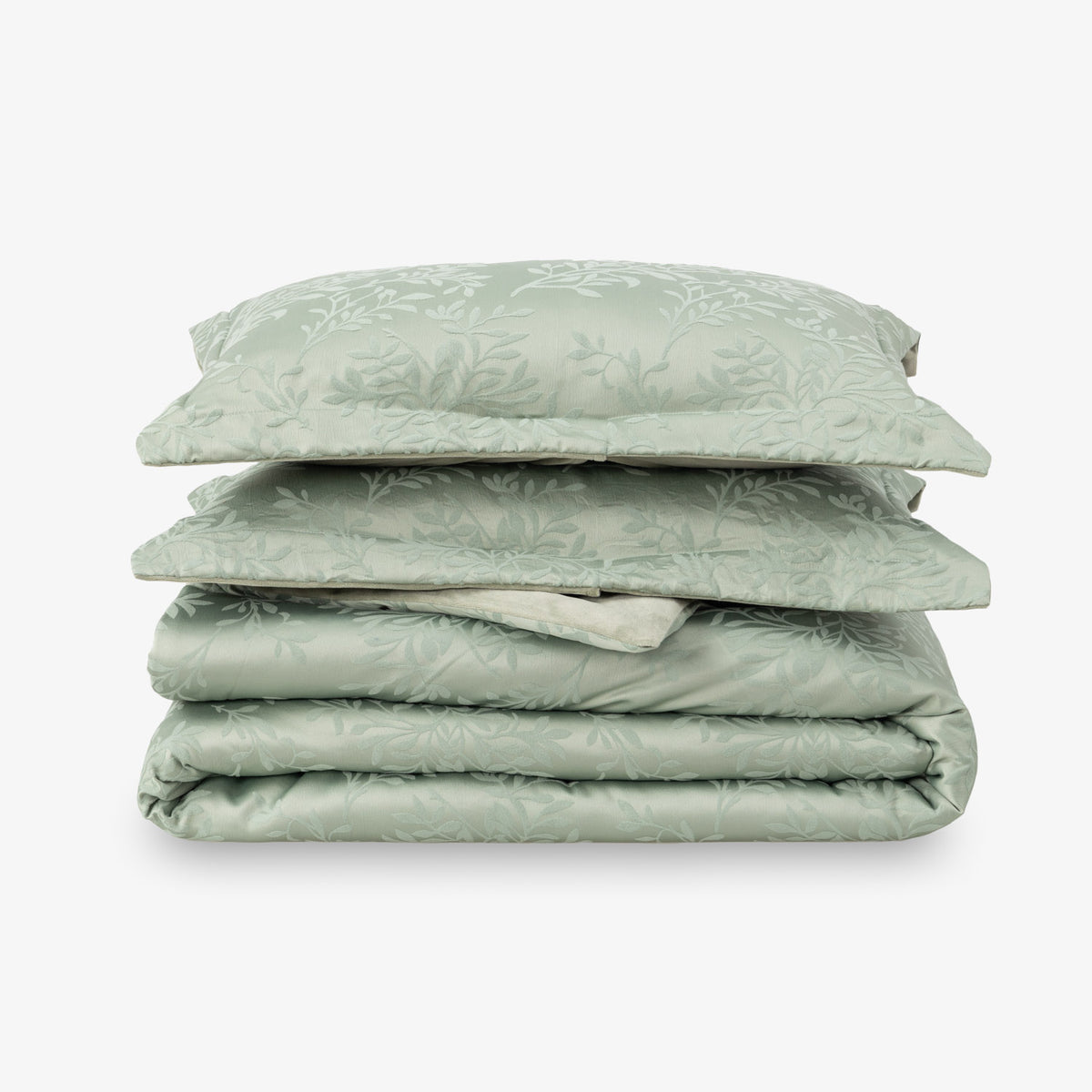 Folded green comforter set with pillows on a white background