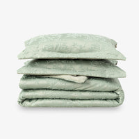 Stack of green floral-patterned bedding on a white background