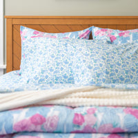 Floral patterned bedding set on a bed with a wooden headboard.