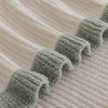 Close-up of a textured fabric with green trim on a beige background