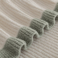 Close-up of a textured fabric with green trim on a beige background