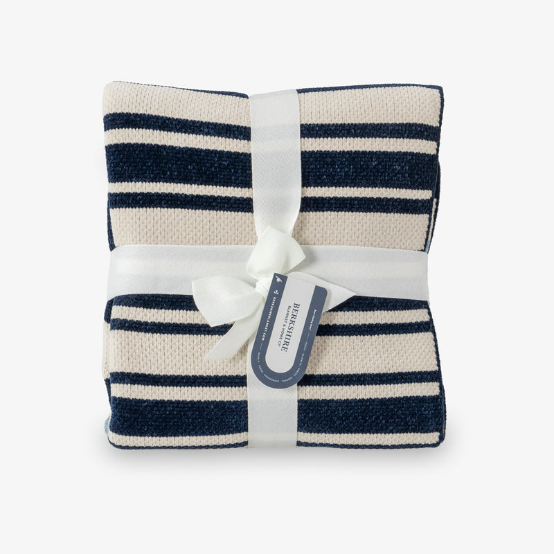 Navy and white striped blanket with a white ribbon and tag on a light gray background