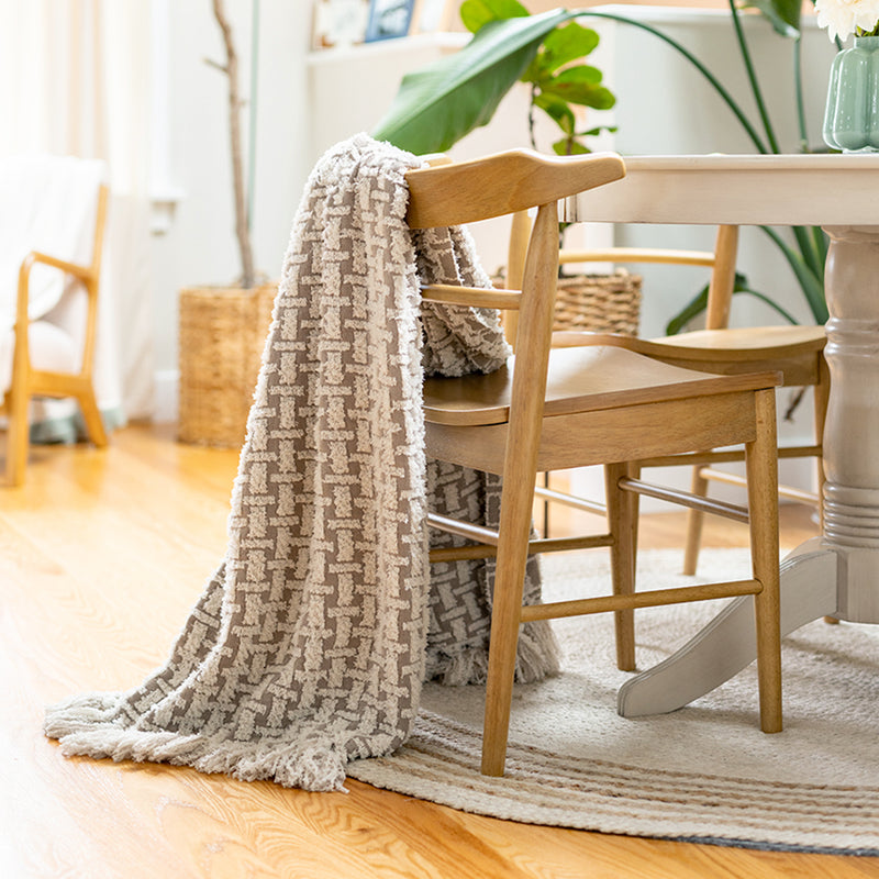 Dining room with wooden chairs and a patterned throw blanket draped over one chair.