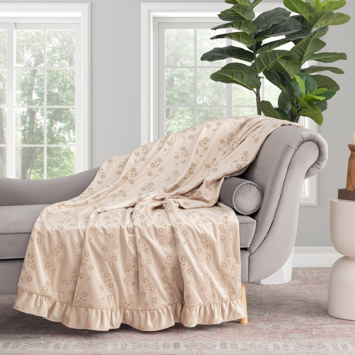Eyelet ruffle throw draped over the arm of a grey chair in a staged room.