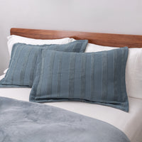Blue striped pillows on a bed with a wooden headboard.