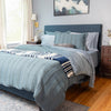 Bedroom with a neatly made bed featuring blue and gray bedding.