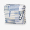 Folded blue and white checkered quilt with a tag on a white background