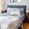 Bedroom with a blue upholstered bed and striped bedding (Quilt & Shams) and Blue VelvetLoft Sheets