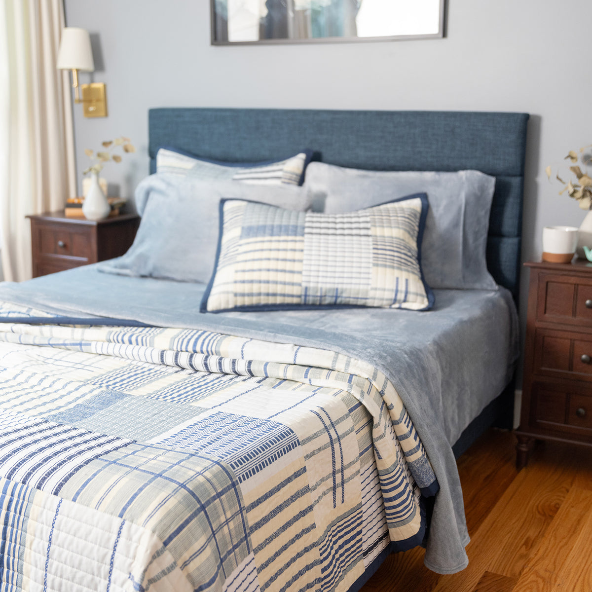Bedroom with a blue upholstered bed and striped bedding (Quilt & Shams) and Blue VelvetLoft Sheets