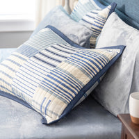 Striped pillows on a bed with a side table in the background