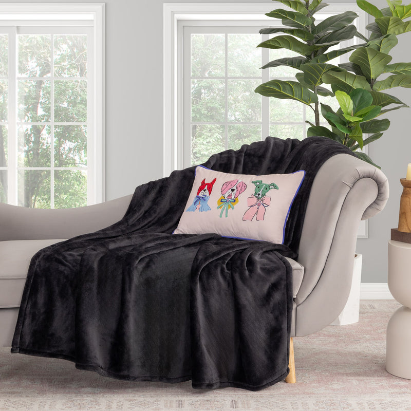 Krissy Mast dog printed pillow sitting on a black throw draped over a grey chair.