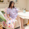 Woman in a floral outfit sitting on a couch in a living room.