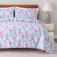 Floral bedding set on a bed with a lamp and nightstand in the background.