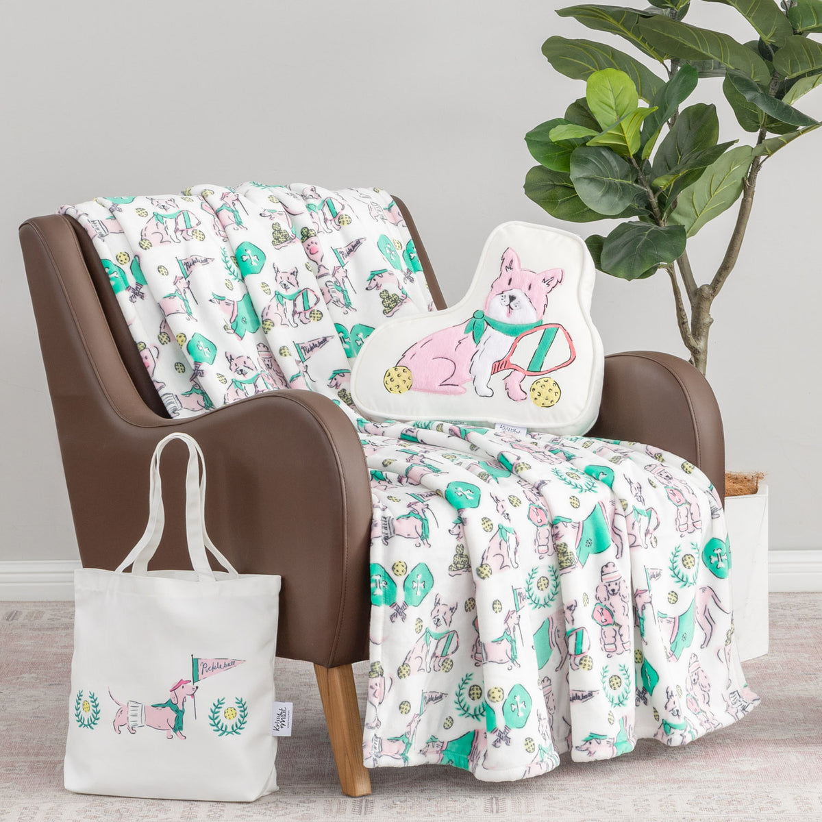 Pickleball pups gift set including a tote, pillow, and throw sitting on a brown chair.