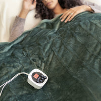 Woman lying under a green heated blanket with a control panel on a white background