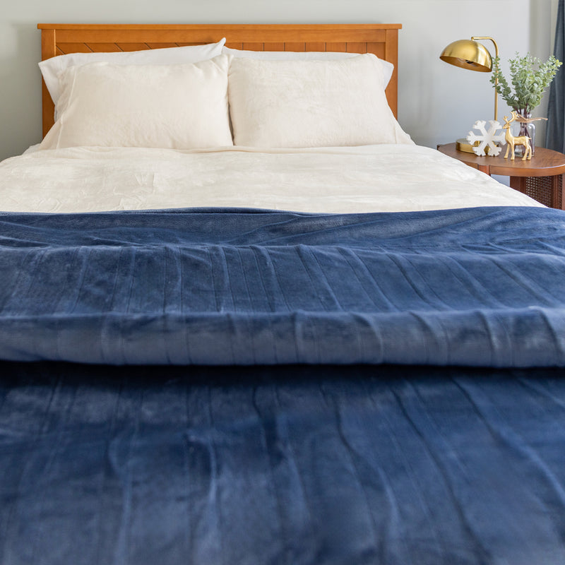 A woman sitting on a bed with a blue heated blanket.